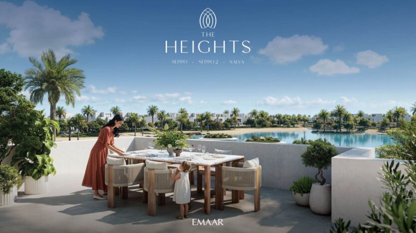 A woman and a child set up an outdoor dining table on a sunny terrace in The Heights, overlooking a lake, palm trees, and modern houses. The clear blue sky adds to the serene atmosphere. The text reads "The Heights" and "EMAAR."