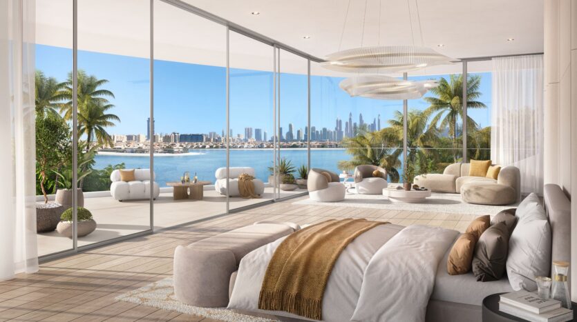 A luxurious Bella by Passo bedroom with floor-to-ceiling windows opens onto a spacious balcony with modern seating, overlooking palm trees, water, and the city skyline in the distance under a clear, bright sky.