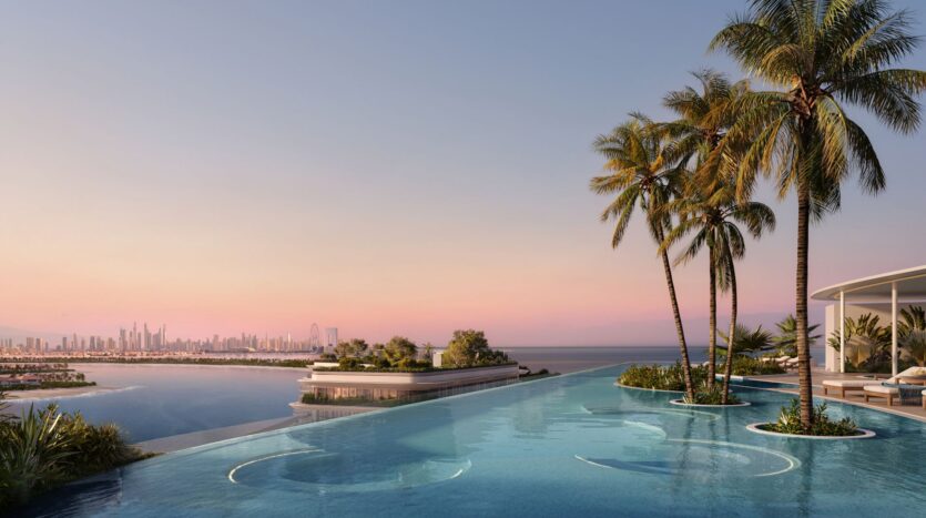 Infinity pool with circular seating and palm trees at Bella by Passo, overlooking the ocean and the distant city skyline at sunset. The pink and purple sky creates a tranquil and luxurious atmosphere.