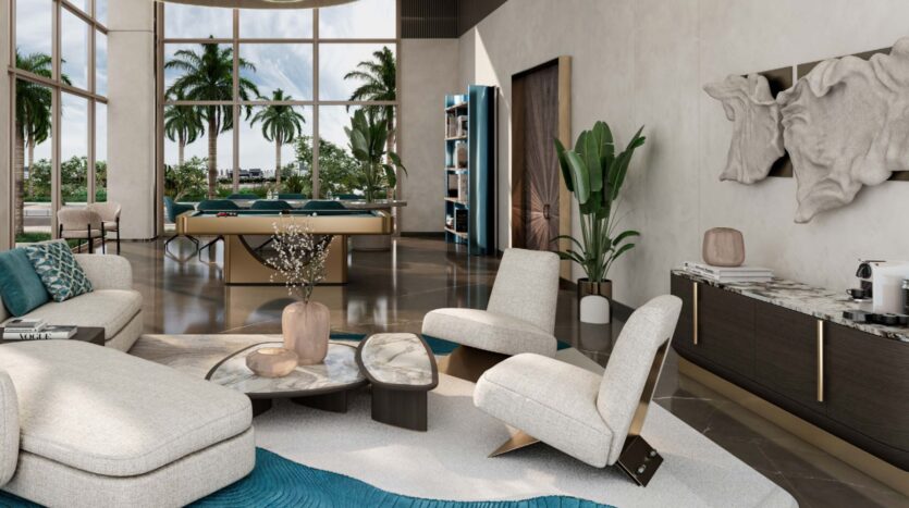 Modern living room with large windows overlooking Flora Bay, tropical plants outside, light-colored furniture, a blue carpet, marble coffee tables, a bookcase, a pool table, and decorative wall art. Natural light illuminates the spacious interior.