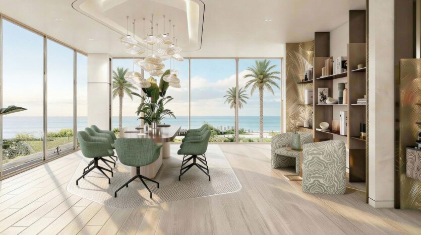 A modern dining room with elegant décor, green chairs, and large windows overlooking the palm trees of Flora Bay, the patio, and the ocean. Sunlight fills the space, highlighting the stylish shelves and indoor plants.
