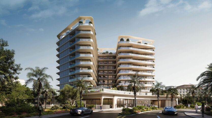 A modern multi-story building with curved balconies and glass facades, the Inara residence is surrounded by palm trees and landscaping. Cars are parked at the entrance, and a sign reading "WAVTAZ" is located near the base.