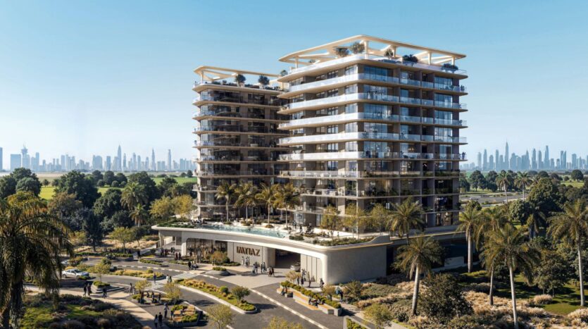 The Inara residence is a modern multi-story residential building with large balconies, surrounded by palm trees and landscaped gardens. A sparkling swimming pool is located at the front, with the distant city skyline visible under a clear blue sky.