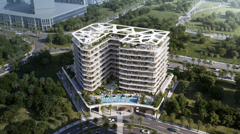 Aerial view of the Inara residence, a modern multi-story building with curved balconies, a white geometric structure on the roof, rooftop gardens, and a swimming pool surrounded by lush vegetation and palm trees in an urban setting.