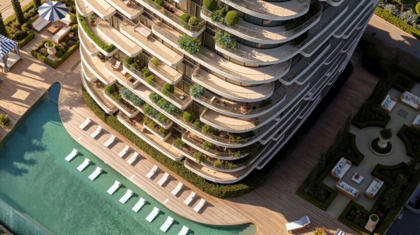 Vue aérienne du Château, une tour moderne avec des balcons incurvés, une végétation luxuriante et une grande piscine extérieure avec des chaises longues et des jardins paysagers en contrebas.