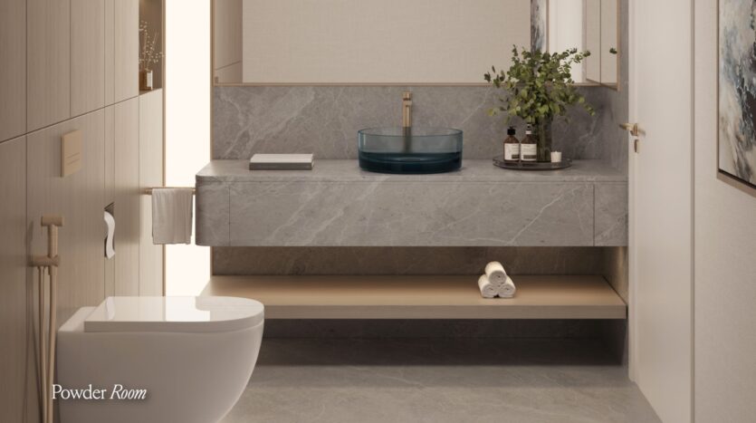 Modern bathroom with a floating Meriva gray marble vanity, a round blue glass sink, a plant and toiletries on the counter, rolled towels on a wooden shelf below, and a white toilet in the foreground.