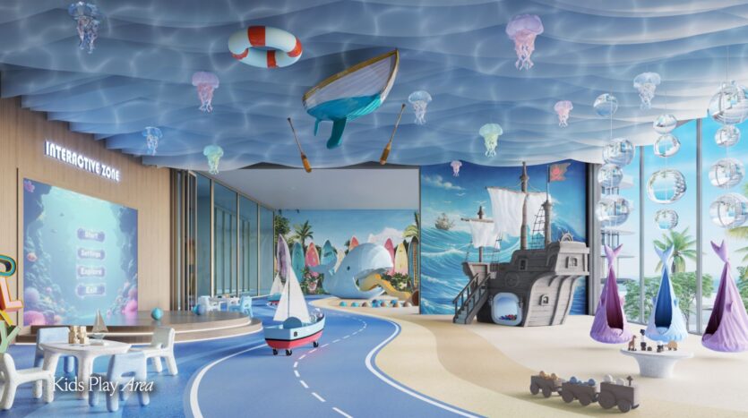 A colorful indoor playground for children, with a sea theme, features a beach mural, a pirate ship, hanging jellyfish, small boats, tables, and an interactive screen, all created with Meriva's creative flair. Blue waves are painted on the ceiling.