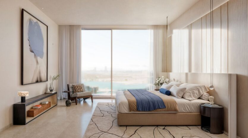 Muheira's modern bedroom with a large window overlooking the water, beige walls, neutral decor, a neatly made bed with blue accents, contemporary artwork, a striped rug, and minimalist furniture.