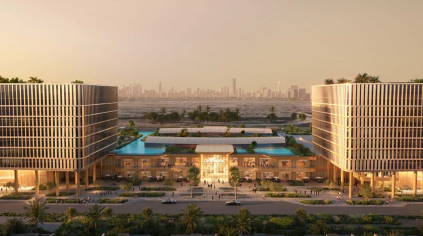 Due moderni edifici in vetro incorniciano un complesso centrale con piscine sui tetti, palme e persone che camminano nella Piazza Roma sottostante. La scena si svolge al tramonto, con lo skyline della città leggermente visibile sullo sfondo.