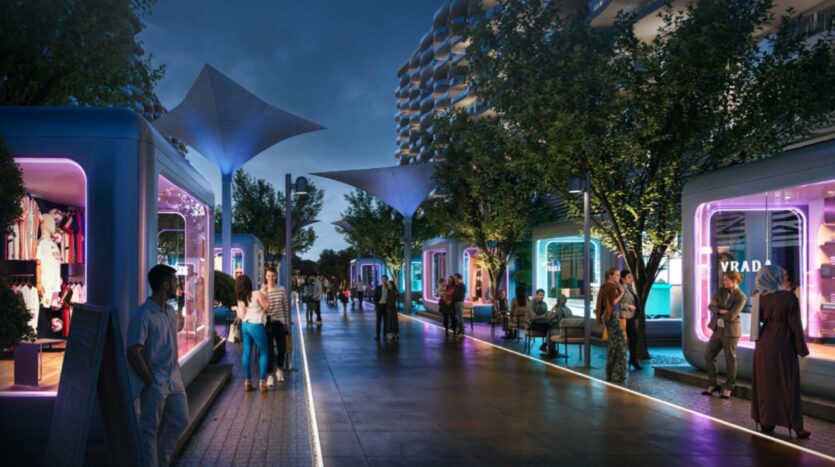 Una moderna strada pedonale al tramonto, con persone che camminano e si siedono. Negozi futuristici con facciate in vetro e illuminazione colorata fiancheggiano entrambi i lati, mentre alberi e tettoie illuminate decorano la vivace scena di Piazza Roma.