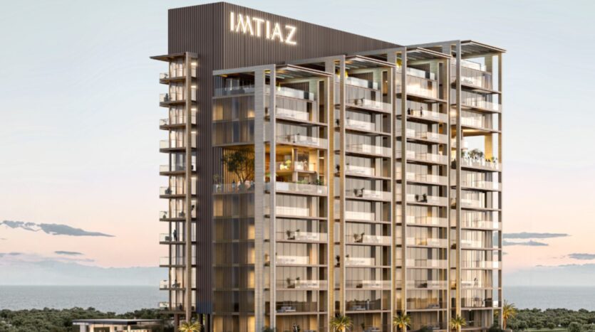 A modern high-rise building with glass balconies, bearing the inscription "IMTIAZ" at the top, stands on Sea Cliff, in a coastal setting with palm trees and a calm sea at sunset.