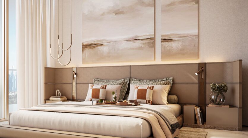 A modern and comfortable bedroom in Sea Cliff with a large bed, neutral bedding, and decorative pillows. Minimalist pendant lights hang above nightstands containing lamps and decorative objects. Abstract paintings and soft natural light complete the soothing atmosphere.