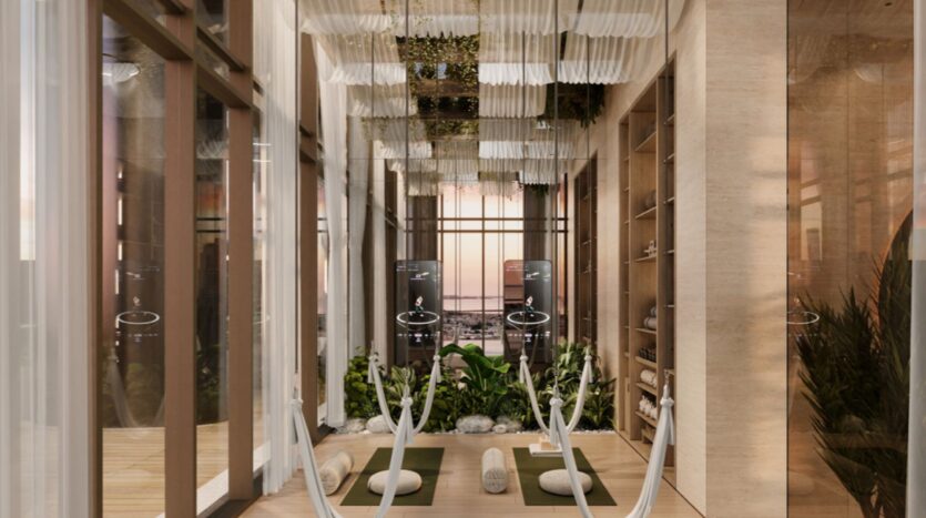 A modern indoor yoga or relaxation space in Sea Cliff features hammocks, yoga mats, bolsters, lush green plants, wooden shelves, and floor-to-ceiling windows; soft lighting and white hanging fabrics create a soothing atmosphere.