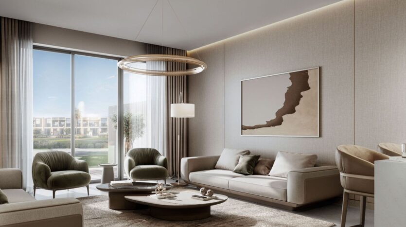 Modern living room in neutral tones at Sobha Sanctuary, featuring two sofas, armchairs, a round coffee table, abstract wall art, large windows with sheer curtains, and a contemporary circular chandelier overlooking a lush outdoor space.