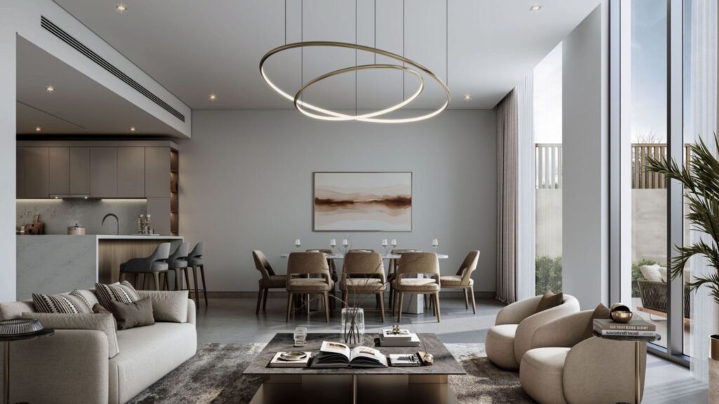 Modern living and dining room at Sobha Sanctuary with neutral colors, large windows, a circular chandelier, plush sofas, a long dining table with chairs, wall art, and a stylish kitchen with bar stools in the background.