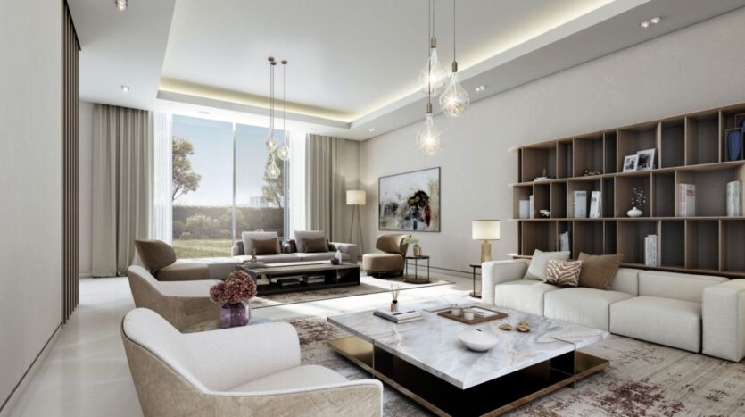 Modern living room at Sobha Sanctuary, featuring neutral tones, white sofas, a marble coffee table, elegant pendant lights, a built-in bookcase, large windows with sheer curtains, and contemporary artwork. Natural light fills the space.