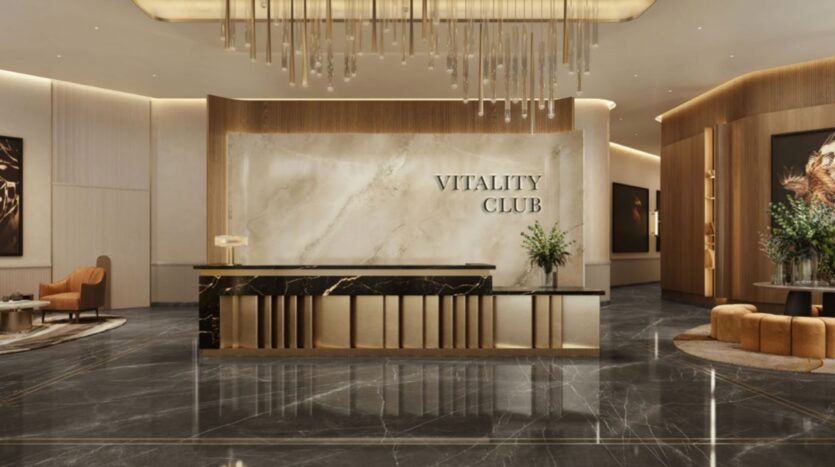 Le hall d'entrée luxueux du Trump Plaza est doté d'un sol en marbre, d'un lustre élégant et d'une réception dont le mur de marbre porte la mention "Vitality Club". Un décor moderne, des sièges en peluche et de la verdure agrémentent cet espace sophistiqué.