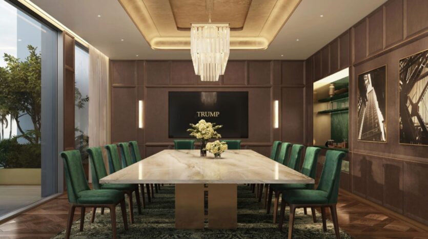 Une luxueuse salle de conférence au Trump Plaza est dotée d'une longue table en marbre, de chaises en velours vert, d'un grand lustre, de centres de table fleuris et de murs lambrissés. De grandes fenêtres inondent l'espace de lumière naturelle, sous un panneau "TRUMP" bien visible sur le mur du fond.