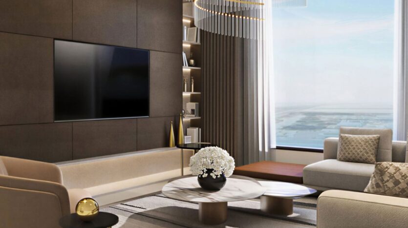 Un salon moderne au Trump Plaza avec une grande télévision murale, des fauteuils beiges, une table basse en marbre avec un arrangement floral blanc, des étagères encastrées et une grande fenêtre offrant une vue imprenable sur la ville et l'eau.