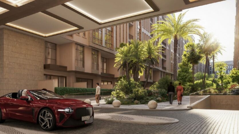 Une voiture de sport décapotable rouge est garée près d'une entrée paysagée avec des palmiers et des buissons au Trump Plaza. Deux personnes marchent le long d'un sentier, avec des immeubles d'habitation modernes visibles à l'arrière-plan éclairé par le soleil.