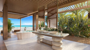 Luxuriöses Open-Air-Badezimmer mit modernen Waschbecken aus Stein und einer freistehenden Badewanne mit Blick auf einen tropischen Strand – ein exklusiver Rückzugsort von Dar Global mit Blick auf den Ozean und den blauen Himmel unter einem Holzdach.