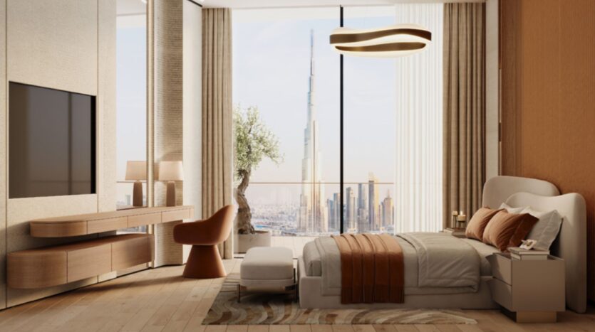 A modern bedroom with neutral and brown decor, a large bed, a television, wooden furniture, and floor-to-ceiling windows offering a view of the cityscape with the Skyflame skyscraper in the background.