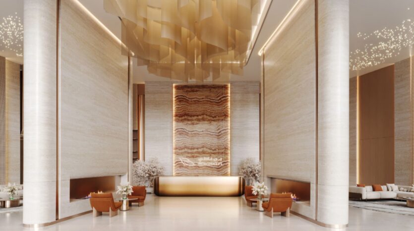 A luxurious and modern lobby featuring tall columns, a spectacular Skyflame gold ceiling sculpture, a large marble reception desk, warm lighting, and elegant seating areas with plush armchairs and decorative plants.