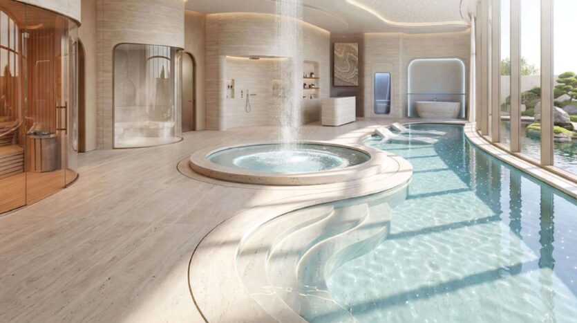 Der luxuriöse Indoor-Spa-Bereich des Greenz by Danube umfasst einen runden Whirlpool mit einem Springbrunnen in der Mitte, ein geschwungenes Schwimmbecken, eine Sauna, einen Duschbereich, große Fenster und eine minimalistische Einrichtung in Beigetönen. Tageslicht durchflutet diesen ruhigen Raum.
