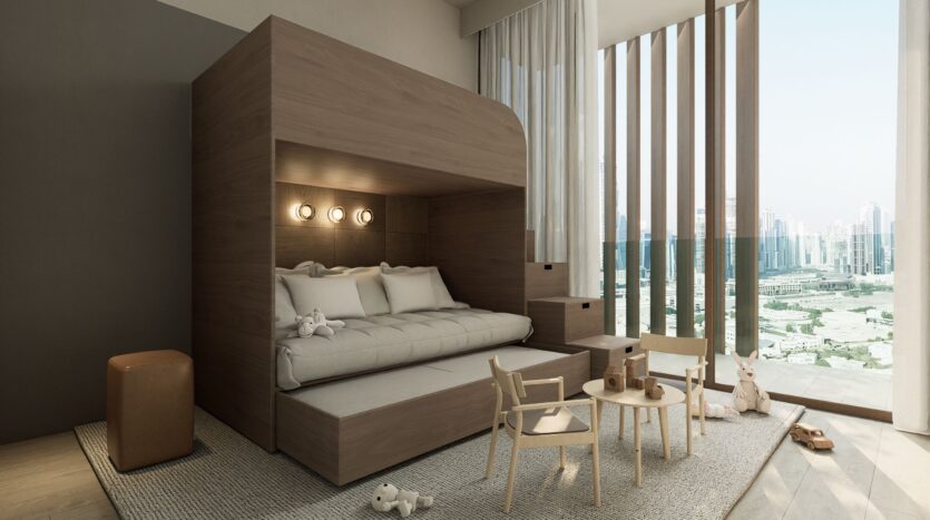 A modern children's room with a wooden bunk bed, a pull-out bed, small chairs, and a round table with toys. Large windows with vertical blinds overlook an urban landscape. This elegant installation highlights the bright and cheerful atmosphere of the JAD288 design.