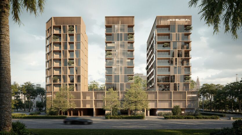 Three modern, medium-sized buildings with wooden facades and vertical lines—part of the JAD288 project—stand side by side, surrounded by trees and greenery, with a blurred car passing in the foreground.
