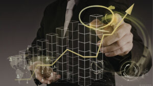 Eine Person im Anzug zeichnet einen nach oben zeigenden gelben Pfeil auf einen transparenten Bildschirm, auf dem digitale Balkendiagramme und futuristische Datenvisualisierungen zu sehen sind, die den Erfolg von Immobilientransaktionen und das Wachstum von Unternehmen symbolisieren.