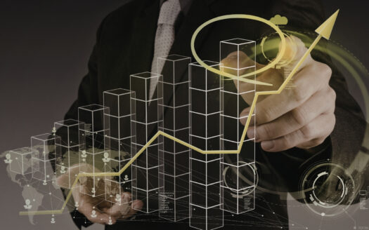 Une personne en costume dessine une flèche jaune montante sur un écran transparent affichant des graphiques à barres numériques et des visualisations de données futuristes, symbolisant le succès des transactions immobilières et la croissance des entreprises.