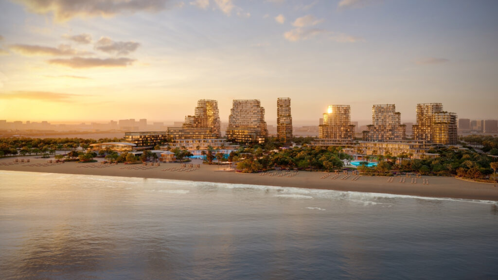 Mitten im Herzen von Dubais Immobilienmarkt erstrahlt ein moderner Strandkomplex mit seinen Glastürmen und üppiger Vegetation im goldenen Licht des Sonnenuntergangs, das sich im ruhigen Wasser spiegelt. Entlang des friedlichen Ufers säumen Sonnenliegen den Sandstrand.