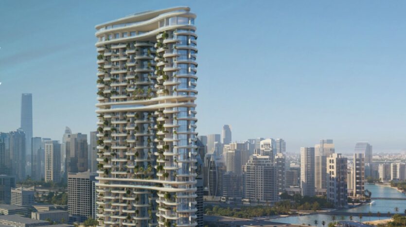 Amali Residences es un moderno rascacielos con balcones curvos y zonas verdes que se alza en el horizonte de la ciudad, rodeado de otros grandes edificios y de un río bajo un cielo azul cristalino.