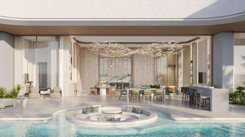Espacio habitable moderno y diáfano de las residencias Amali, con grandes puertas acristaladas que dan a un salón circular situado a un nivel inferior y rodeado por una piscina; decoración elegante, tonos neutros y mobiliario contemporáneo.