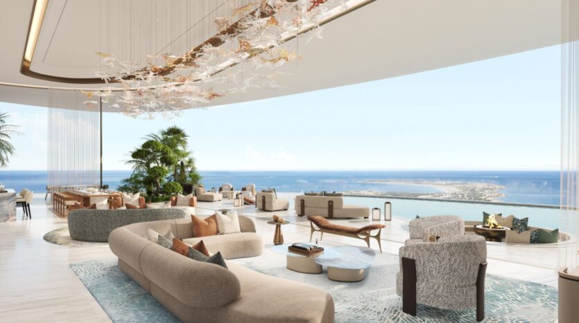 El lujoso y moderno salón de las residencias Amali cuenta con sofás curvos y grandes ventanales que ofrecen unas vistas panorámicas del océano. La elegante decoración incluye plantas, una iluminación singular y muebles en tonos neutros, lo que crea un ambiente diáfano y relajante.