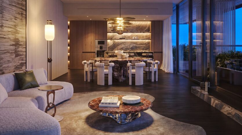 The modern and elegant living and dining rooms in the Cheval residences feature a curved sofa, a round marble coffee table, an elegant dining table with white chairs, stylish lighting, wood accents, and large glass doors that open onto a balcony at dusk.