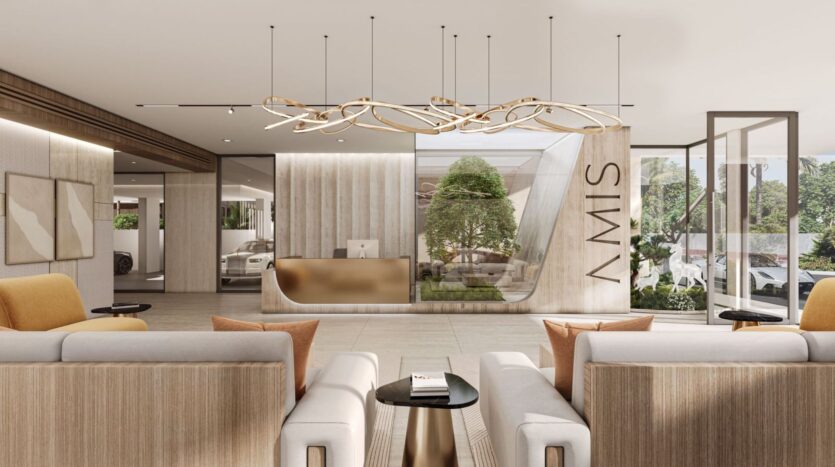 The modern lobby at Derby Heights features sofas and armchairs in neutral tones and an elegant reception desk. Large windows, houseplants, abstract artwork, and a sculptural chandelier create a welcoming atmosphere. The word "SWIM" is displayed on one of the walls.