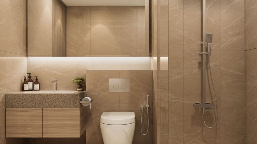 A modern bathroom in Derby Heights featuring beige marble walls, a floating wooden vanity with a sink, a mirror, a toilet, a bidet, and a glass-enclosed shower. Two bottles and a small plant sit on the countertop. The lighting is soft and diffused.