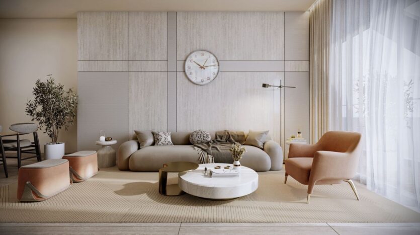 A modern living room in Derby Heights decorated in neutral tones, featuring a large beige sofa, a pink armchair, a white round coffee table, a wall clock, a floor lamp, and large windows with sheer curtains that let in natural light.