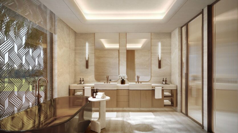 A luxurious modern bathroom at Four Seasons Private Residences featuring a dark freestanding bathtub, two sinks, large mirrors, soft lighting, beige stone walls, and decorative glass panels. A small white table and towels are neatly arranged.