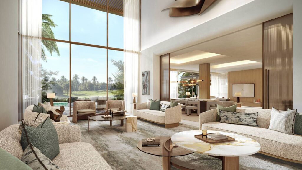 A spacious, modern living room in the Four Seasons private residences, featuring floor-to-ceiling windows, neutral-toned sofas, a marble coffee table, and outdoor greenery. The open-concept layout leads to a well-lit dining room with contemporary décor.