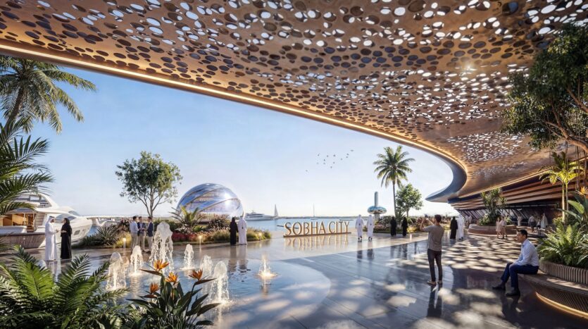 A futuristic waterfront setting featuring a perforated canopy, palm trees, water features, people strolling by, and a metal dome near the sea evokes the elegance of the River Cove residences. The sign reads "SOBHA CITY" against a clear blue sky.