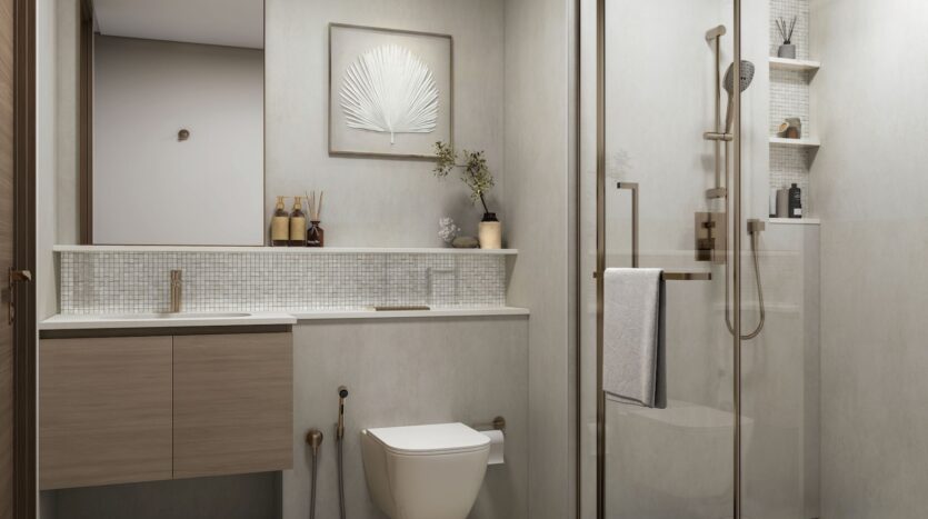 The modern bathroom at River Cove Residences features light beige walls, a driftwood vanity, a wall-mounted toilet, and a glass shower. Minimalist fixtures and framed art prints complete this serene space.