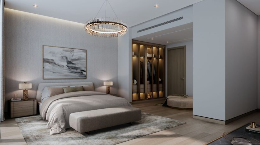 Modernes Schlafzimmer im „The Orchard by Sobha“ mit einem großen Bett, neutraler Bettwäsche und einer gepolsterten Sitzbank am Fußende. Ein beleuchteter Schrank, abstrakte Wandkunst, ein eleganter Kronleuchter und sanfte Beleuchtung schaffen eine gemütliche und stilvolle Atmosphäre.