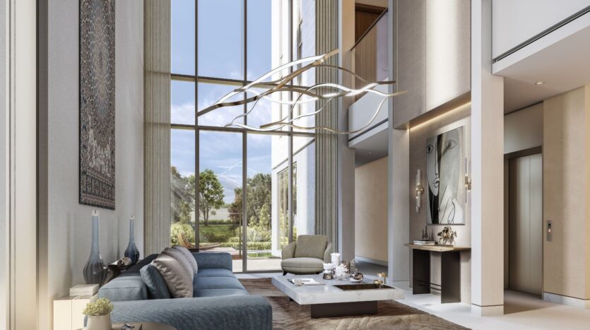 Ein modernes, luftiges Wohnzimmer im „The Orchard by Sobha“ mit raumhohen Fenstern, neutralen Farbtönen, einem blauen Sofa, einem abstrakten Kronleuchter, einem Couchtisch aus Marmor, Wandkunstwerken und einem großen Wandteppich – und das alles mit Blick auf einen üppigen Garten mit Bäumen und viel Grün.