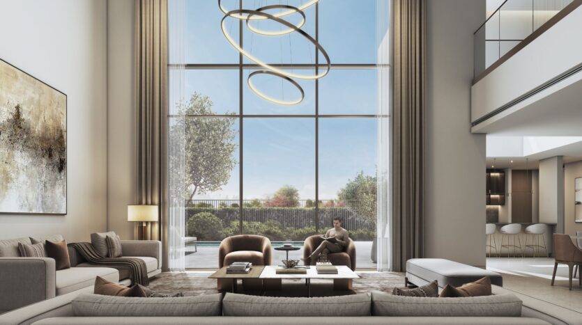 Geräumiges, modernes Wohnzimmer im „The Orchard by Sobha“ mit hohen Fenstern, einem modernen runden Kronleuchter, Sofas in neutralen Farbtönen, Sesseln, einem großen Couchtisch, Wandkunstwerken und Blick auf den Garten. Eine Person sitzt am Fenster und liest friedlich.