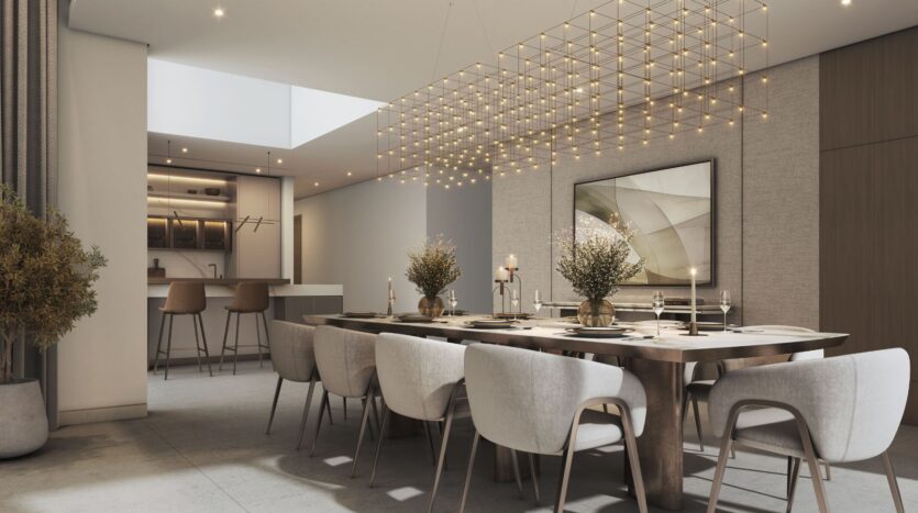 Ein modernes Esszimmer mit einem großen Holztisch, weißen Polsterstühlen, minimalistischer Einrichtung und einem gitterförmigen Kronleuchter. Die Wände in neutralen Farbtönen runden das Gesamtbild ab, während die Küche mit ihren Barhockern die für „The Orchard by Sobha“ typische Eleganz widerspiegelt.