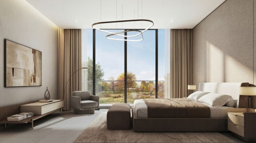 A modern bedroom at The Terraces by Sobha featuring a king-size bed, neutral tones, elegant lighting fixtures, an armchair, artwork on the walls, and large floor-to-ceiling windows offering bright views of the trees and the natural landscape.