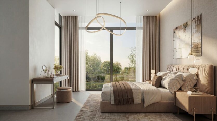 The modern bedroom at The Terraces by Sobha features a large window, beige walls, a double bed with pillows and a blanket, two nightstands with lamps, a vanity with a stool, and soft natural light that fills the room.
